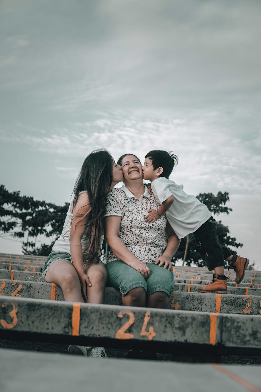 a young boy and a woman kissing an elderly woman